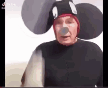 an elderly man is wearing a mickey mouse costume and a mickey mouse hat .