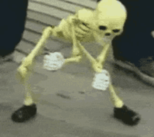 a yellow skeleton is standing on its hind legs on a sidewalk .