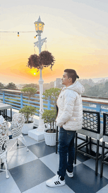 a man in a white jacket stands in front of a street light at sunset