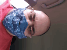 a bald man wearing glasses and a blue bandana