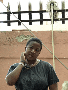 a woman stands in front of a fence and a mop