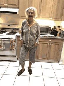 an elderly woman in pajamas stands in a kitchen