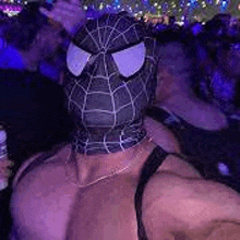 a man wearing a spider-man mask is standing in front of a crowd of people .