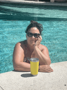 a woman sitting in a pool with a yellow cup