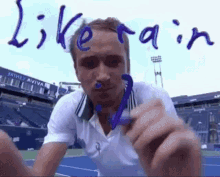 a man in a white shirt is holding a purple object in front of a sign that says like rain