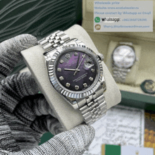 a person is holding a silver rolex watch