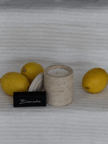 a candle sits on a white cloth next to lemons and a sign that says blanche