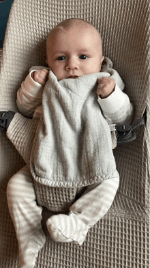 a baby is laying in a bouncer holding a blanket