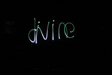 the word divine is written with green lights on a black background