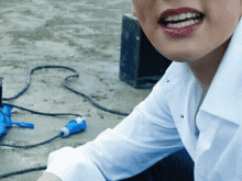 a woman wearing a white shirt and red lipstick smiles while sitting on the ground