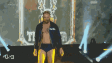 a shirtless wrestler is walking on a stage with a usa logo in the background