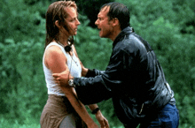 a man in a leather jacket is holding a woman in his arms