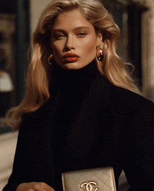 a woman wearing a black turtleneck and gold chanel earrings