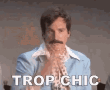 a man with a mustache is wearing a blue jacket and a scarf and is saying trop chic .