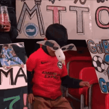 a boy wearing a red american express shirt holds a sign