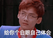 a young man wearing glasses and a blue jacket is making a funny face in a foreign language .