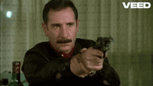 a man with a mustache is pointing a gun at the camera with the word veed in the corner