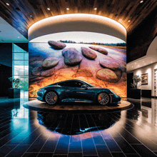 a car is displayed in a showroom with a large screen behind it