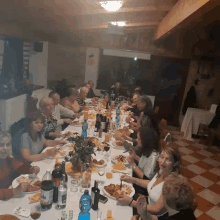 a group of people are sitting at a long table with a bottle of cola on the table