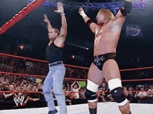 two wrestlers are dancing in a ring with a crowd watching