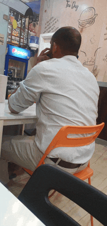 a man sits in front of a pepsi fridge