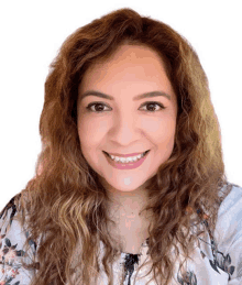 a woman with curly hair and a floral shirt smiles for the camera