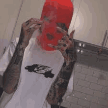 a man wearing a red ski mask and a white shirt is smoking a cigarette in a kitchen .