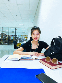 a girl sits at a desk with a book and sunglasses