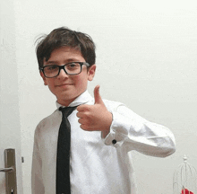 a young boy wearing glasses and a black tie is giving a thumbs up