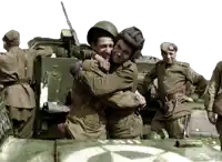 two soldiers hugging each other in front of a tank that has the letter sn on the side