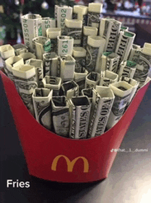 a red mcdonald 's french fries container filled with dollar bills