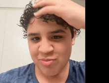 a young man with curly hair looks at the camera