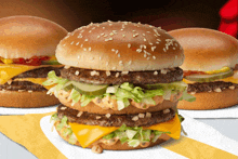 three hamburgers on a yellow and white napkin one of which is a big mac