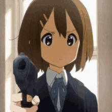 a girl in a suit is holding a gun in her hand .