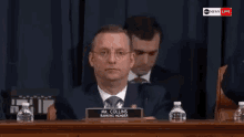 a man in a suit and tie is sitting at a table with a name plate that says mr. collins ranking member