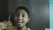 a young boy is making a funny face with a glitchcam watermark on the bottom