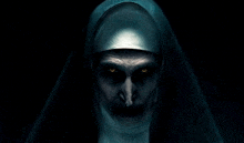 a close up of a nun 's face with glowing eyes in the dark