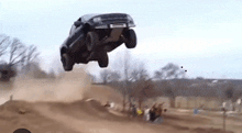 a truck is jumping in the air while driving down a dirt road .