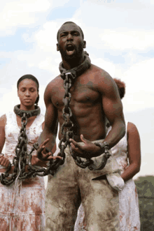 a man with chains around his neck is screaming in front of two women