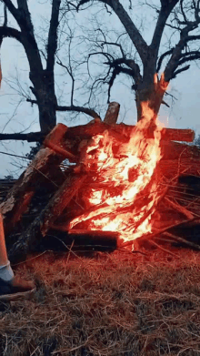 a large pile of logs is burning in the middle of a field