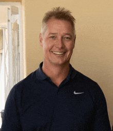 a man wearing a blue nike shirt is smiling for the camera