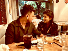 a man and a woman are sitting at a table with drinks and a shirt that says " i love you " on it