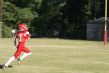 a football player wearing a helmet and red uniform is running on the field