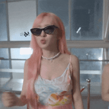 a woman with pink hair is wearing sunglasses and a necklace