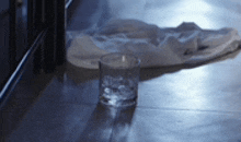 a glass of water sits on the floor next to a white cloth .