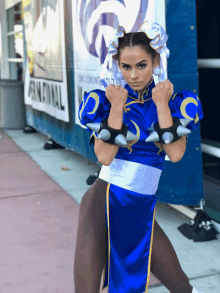 a woman in a blue costume stands in front of a sign that says fanconnal