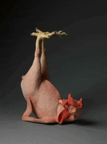 a statue of a chicken laying on its back with its legs up