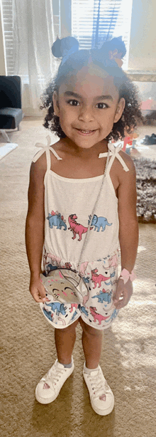 a little girl is wearing a white tank top with elephants on it