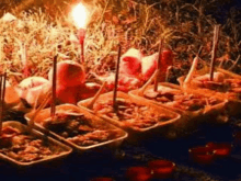 a bunch of containers of food are sitting on a table with candles .