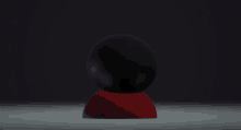 a black egg with purple eyes sits on a red base in the dark